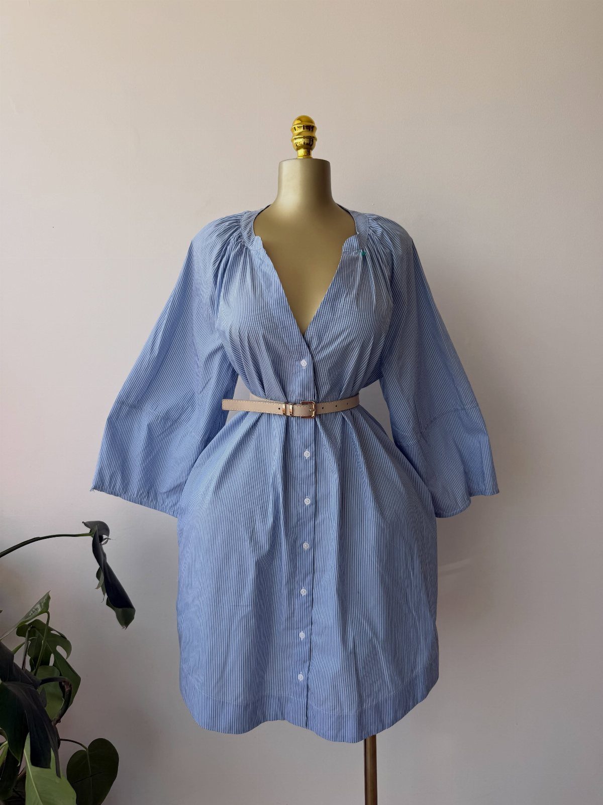Blue and white patterned button down shirt dress with bell sleeves on a mannequin.
