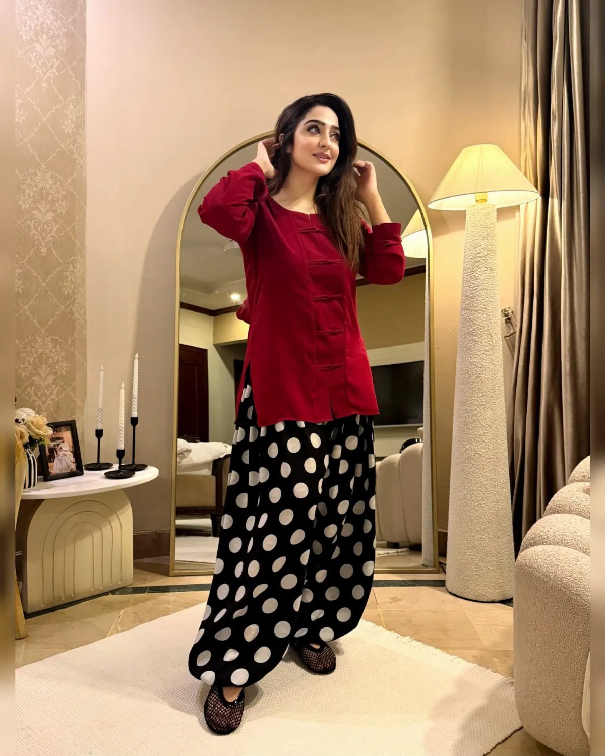 Woman wearing a red tunic and black and white polka dot wide-leg trousers.
