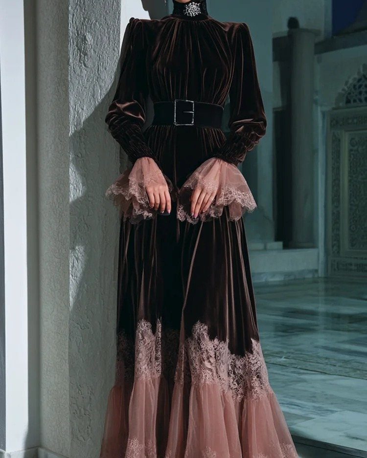 A person wearing a dark brown velvet maxi dress with lace detailing and a black belt.