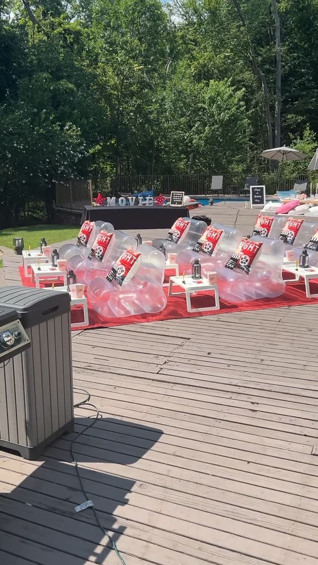 Pink inflatable loungers with popcorn bags arranged on a deck for an outdoor movie night.