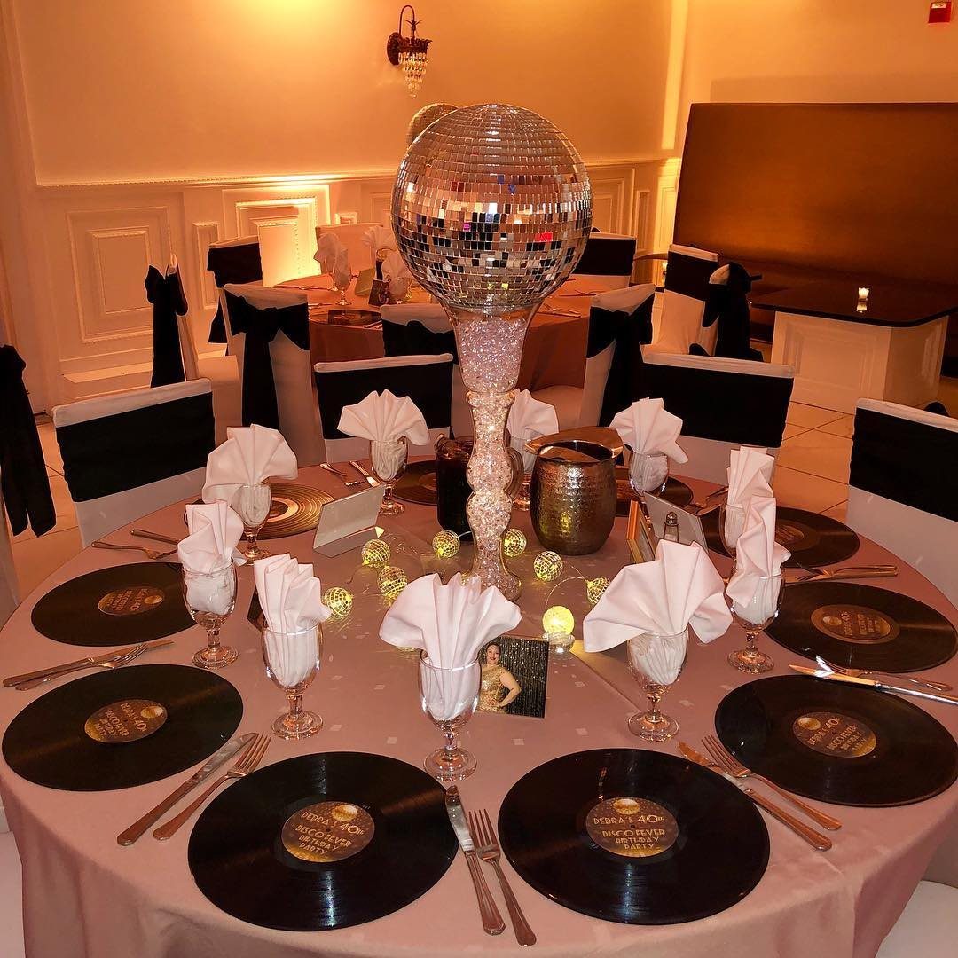A formal dining table set with vinyl record placemats and a large disco ball centerpiece.