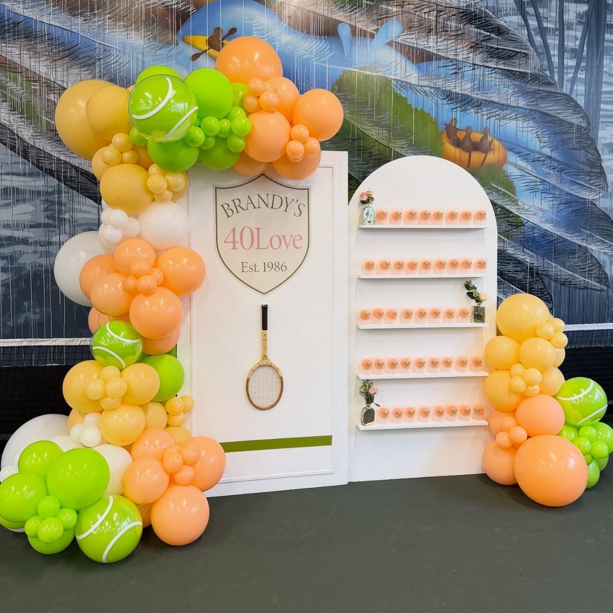 Tennis themed birthday backdrop with orange and green balloon arches and a custom sign.