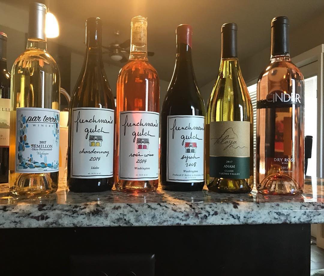 Six assorted wine bottles of different varieties lined up on a granite countertop.