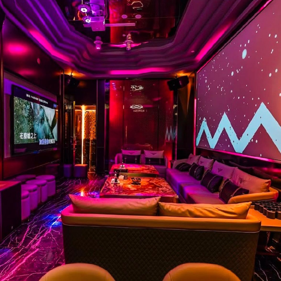 A luxury lounge with purple neon lighting, large screens, and comfortable sofas.