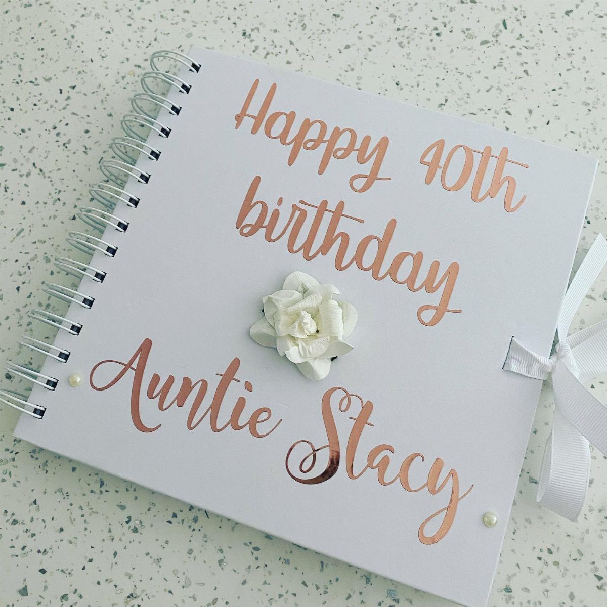 A white spiral notebook with rose gold text celebrating Auntie Stacy's 40th birthday.