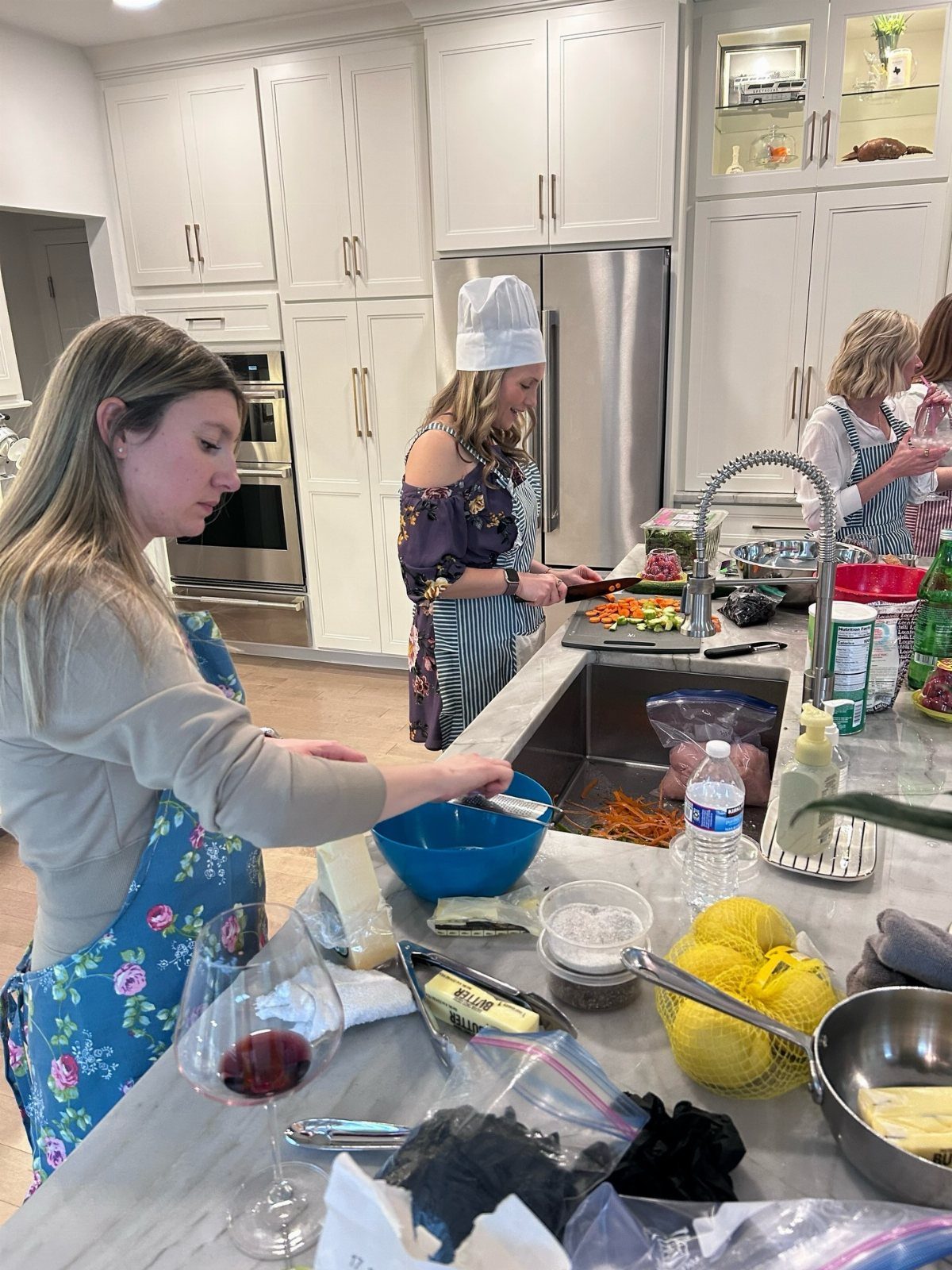 Women preparing food together in a modern kitchen with various ingredients and cooking tools.