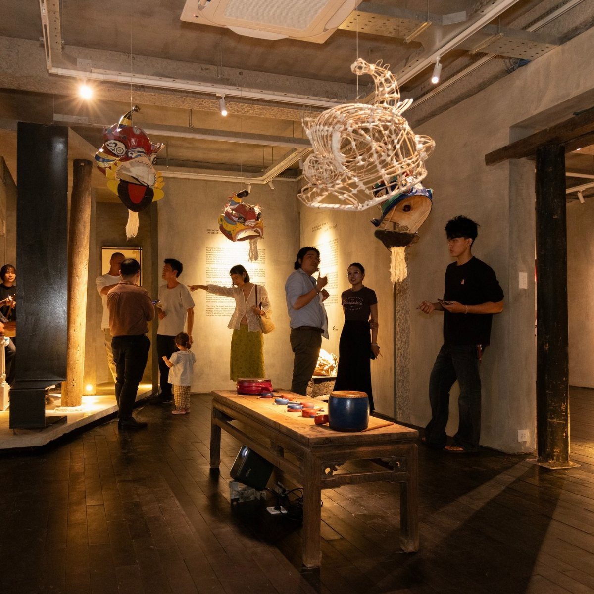 People walking through a modern art gallery featuring large hanging white woven sculptures.