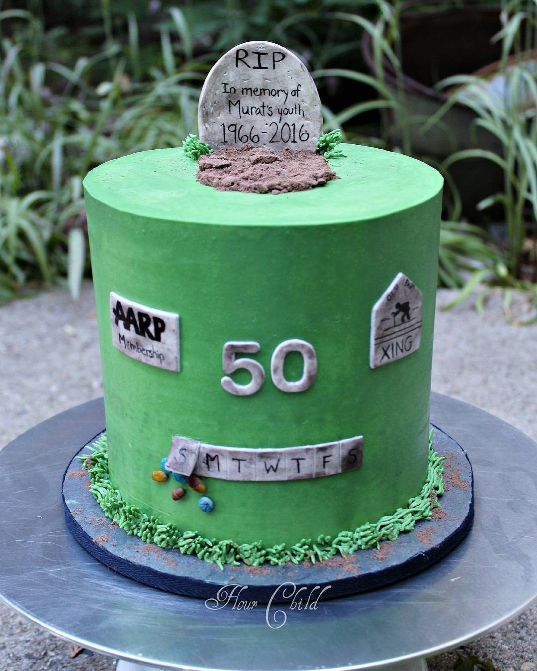 Green humorous cake featuring a small tombstone, the number 50, and AARP membership decorations.