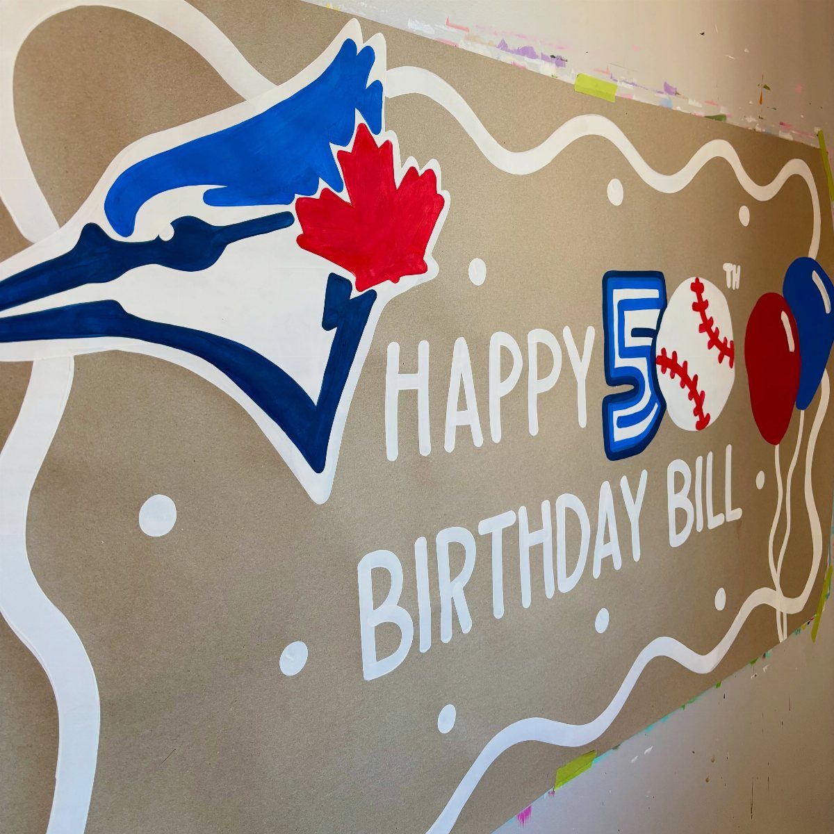 Hand-painted brown birthday banner with a blue jay logo and Happy 50th Birthday Bill text.