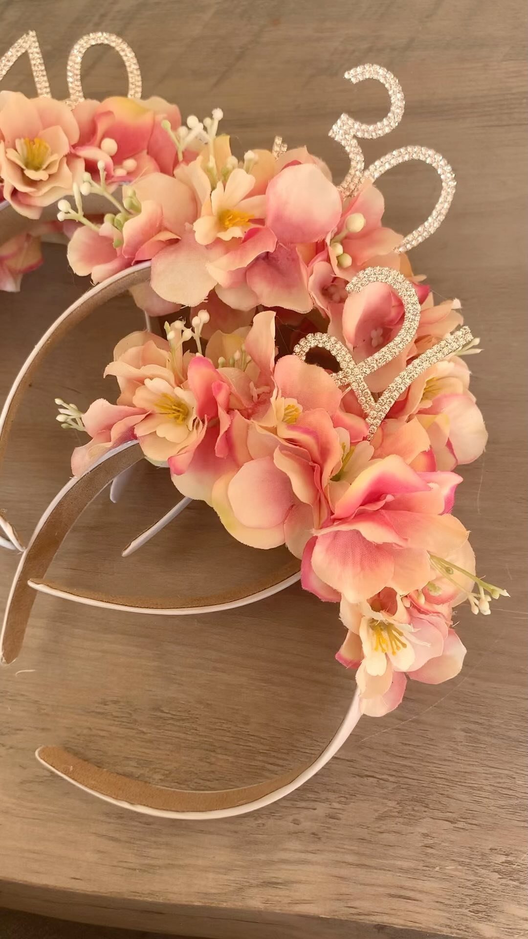 A floral headband featuring pink flowers and glittery silver numbers reading fifty.