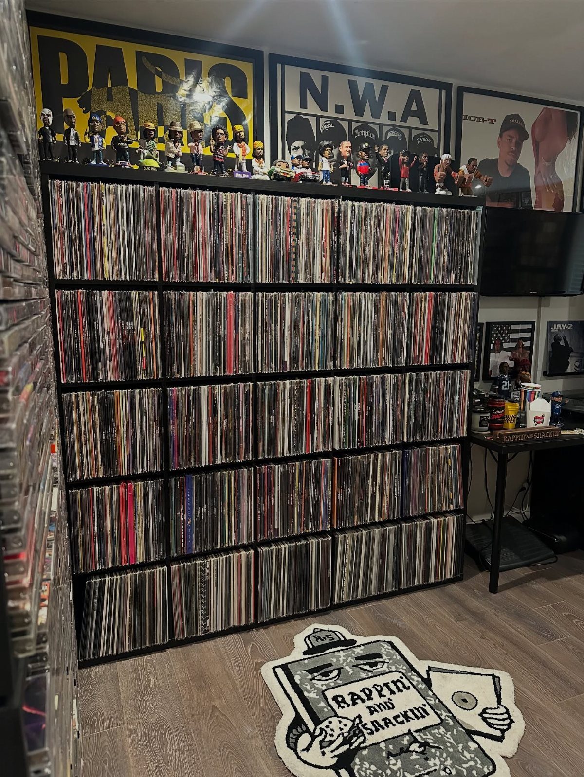 Large black shelves packed with many vinyl record albums and small figurines on top.