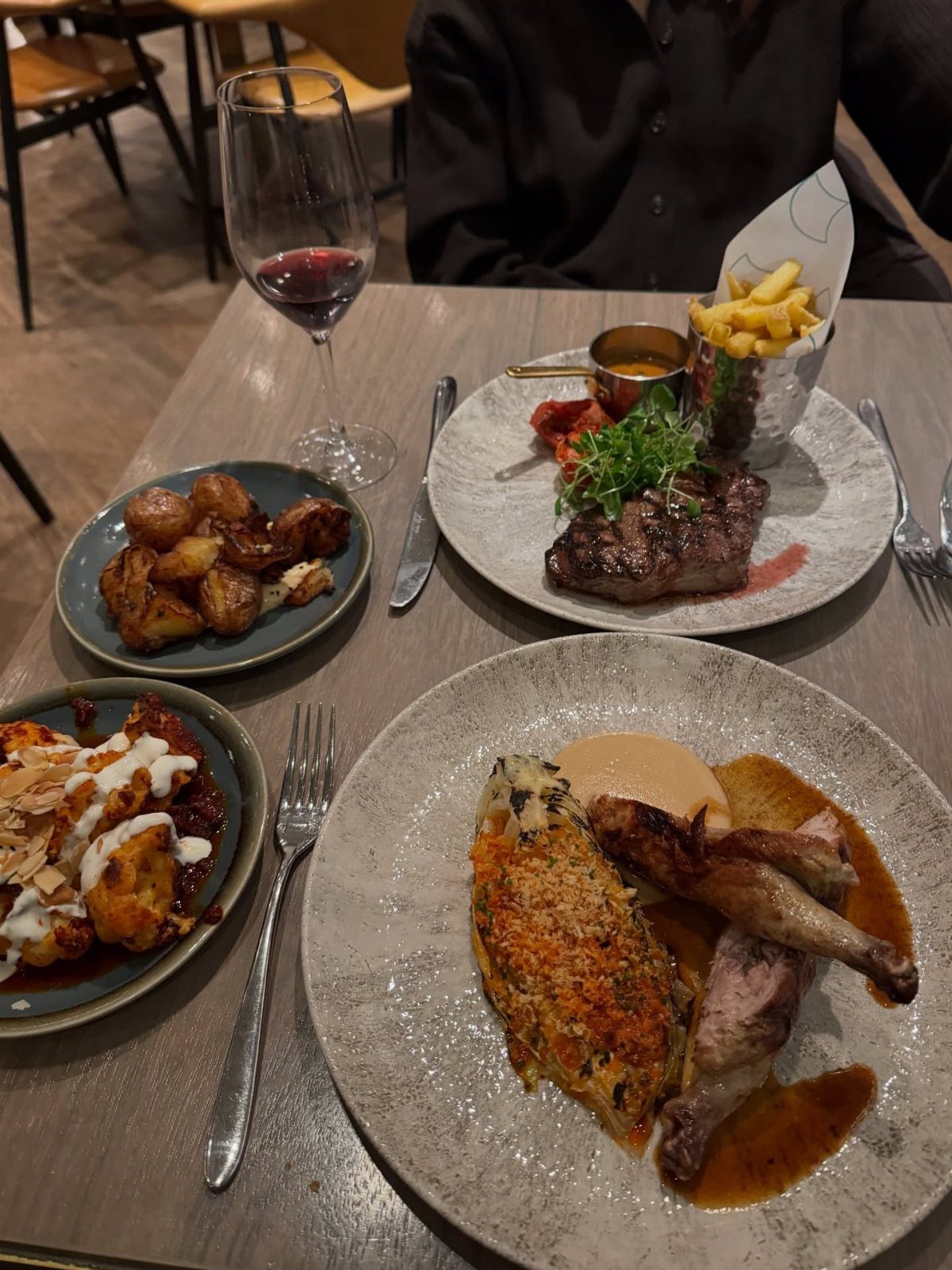 Gourmet plated meals and a glass of red wine on a restaurant table.