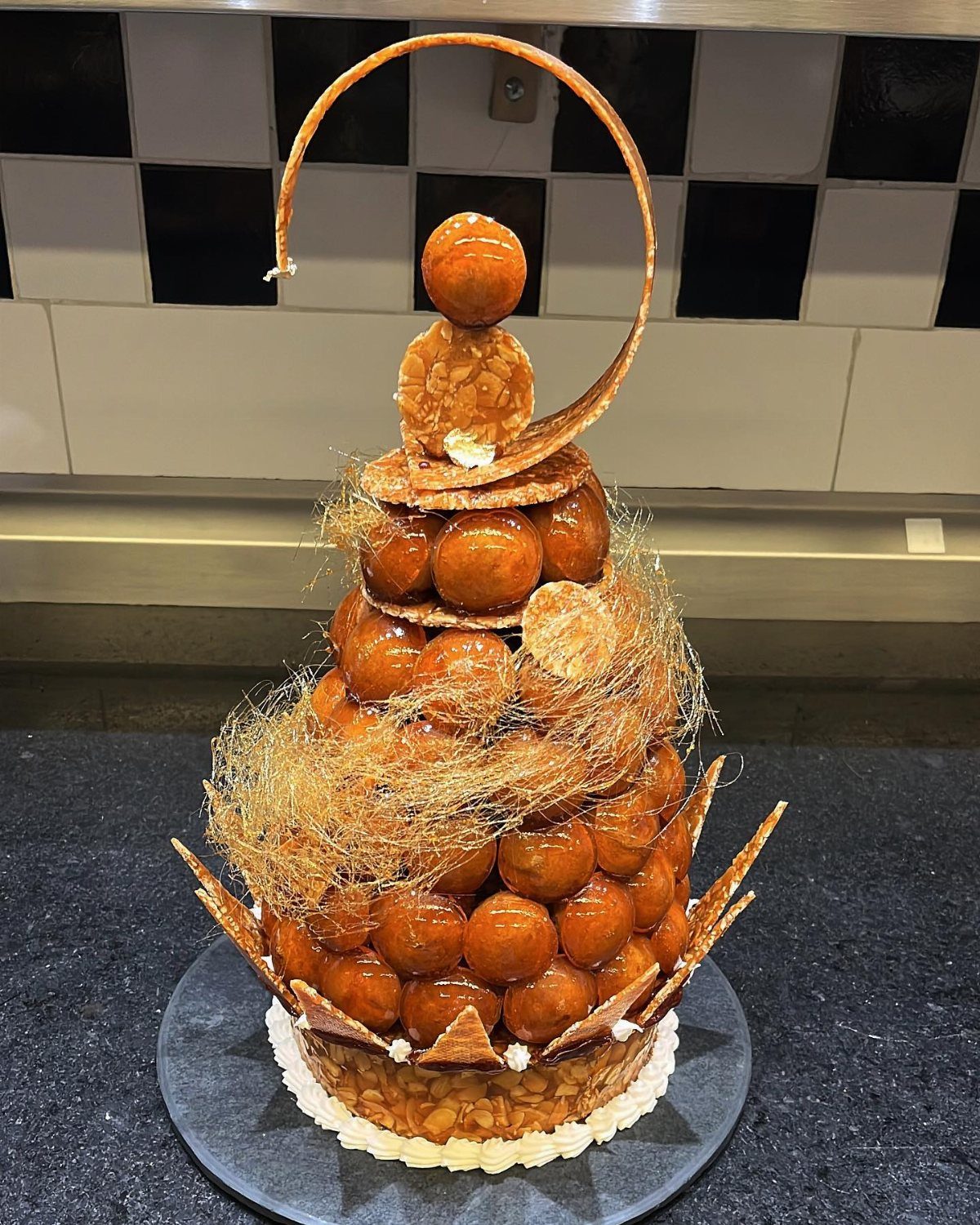 A tall croquembouche tower of caramel-coated profiteroles with spun sugar decorations.