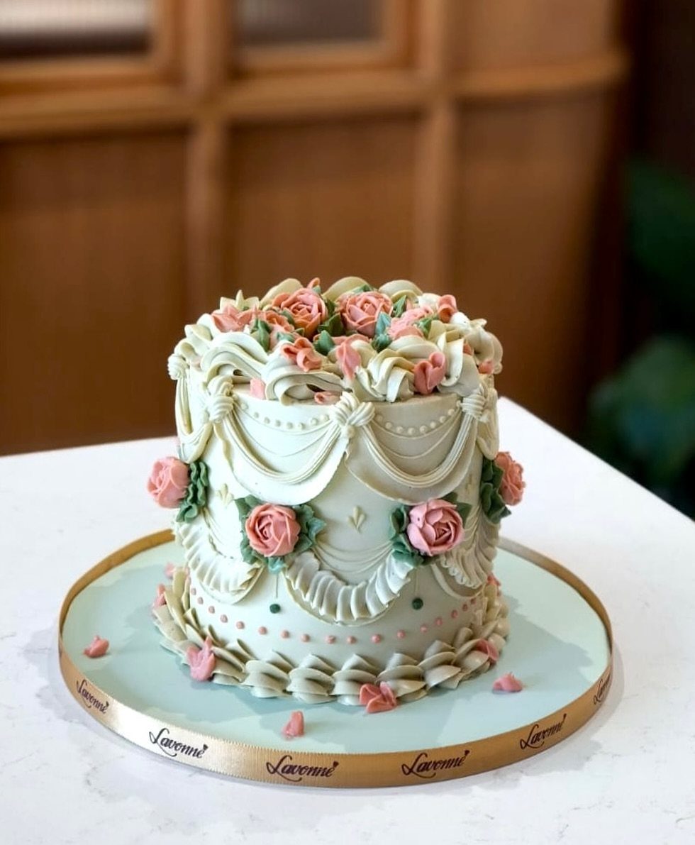 A mint green buttercream cake decorated with pink roses and elegant piped swags.