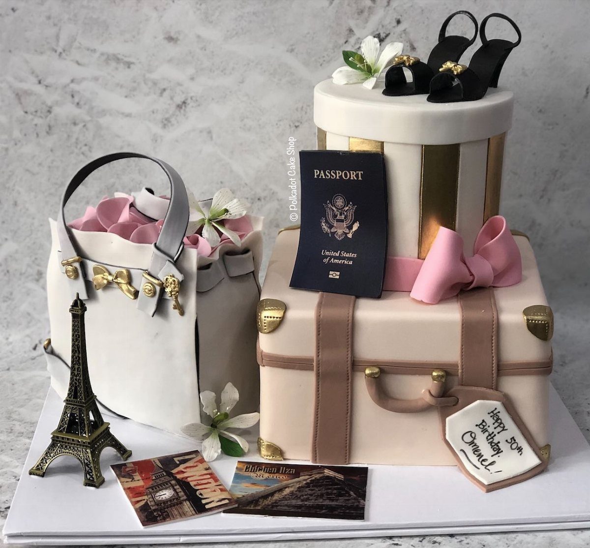 A tiered cake designed as a vintage suitcase, handbag, and travel accessories.