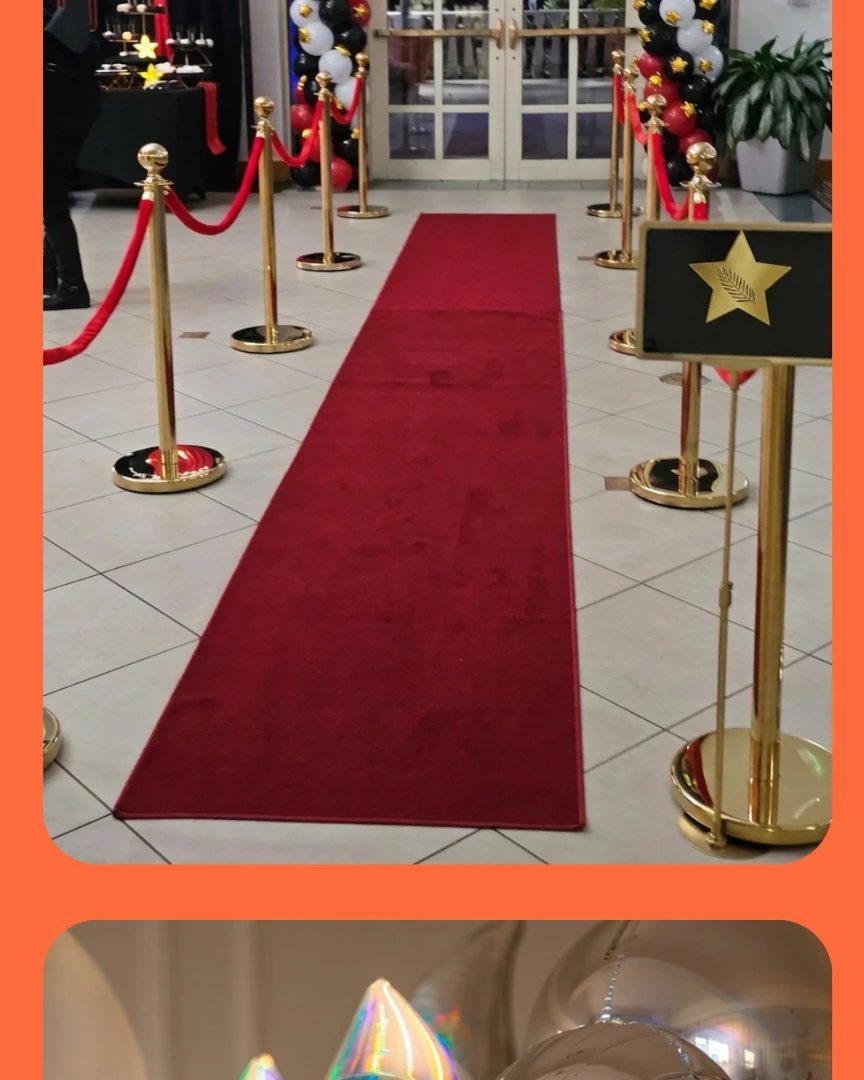 Red carpet runner lined with gold stanchions and red velvet ropes on a tiled floor.