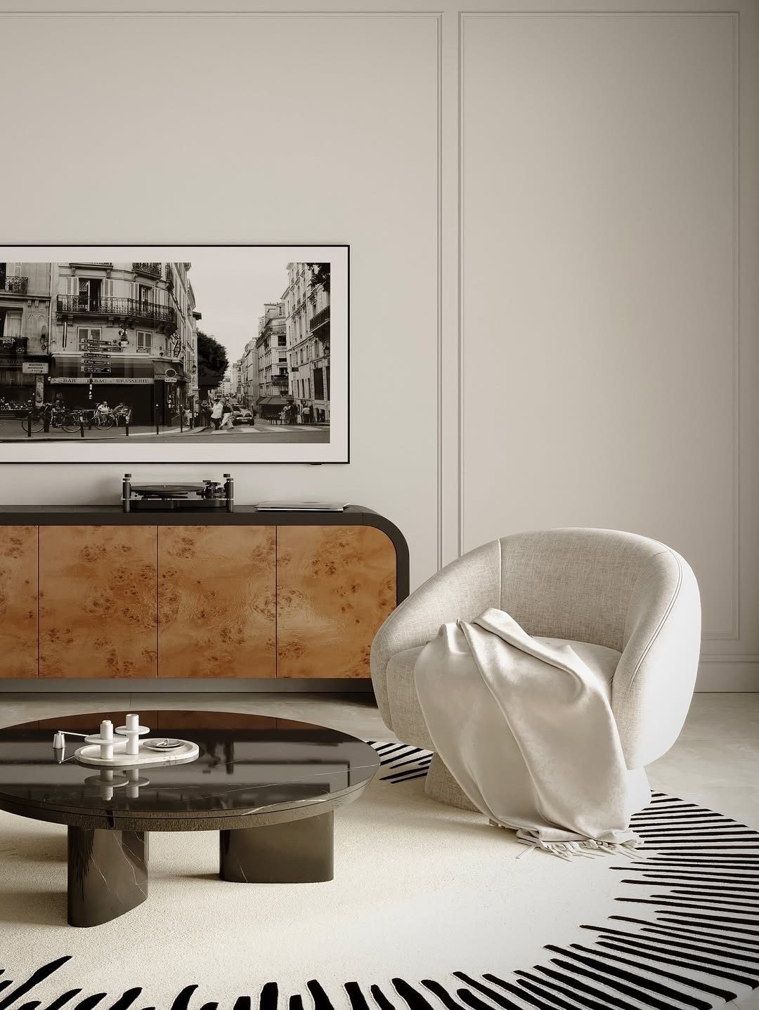 Minimalist living room with cream armchair, dark coffee table, and black and white wall art.
