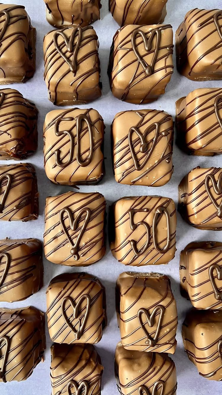 Square caramel chocolates decorated with dark chocolate hearts and the number fifty on white paper.