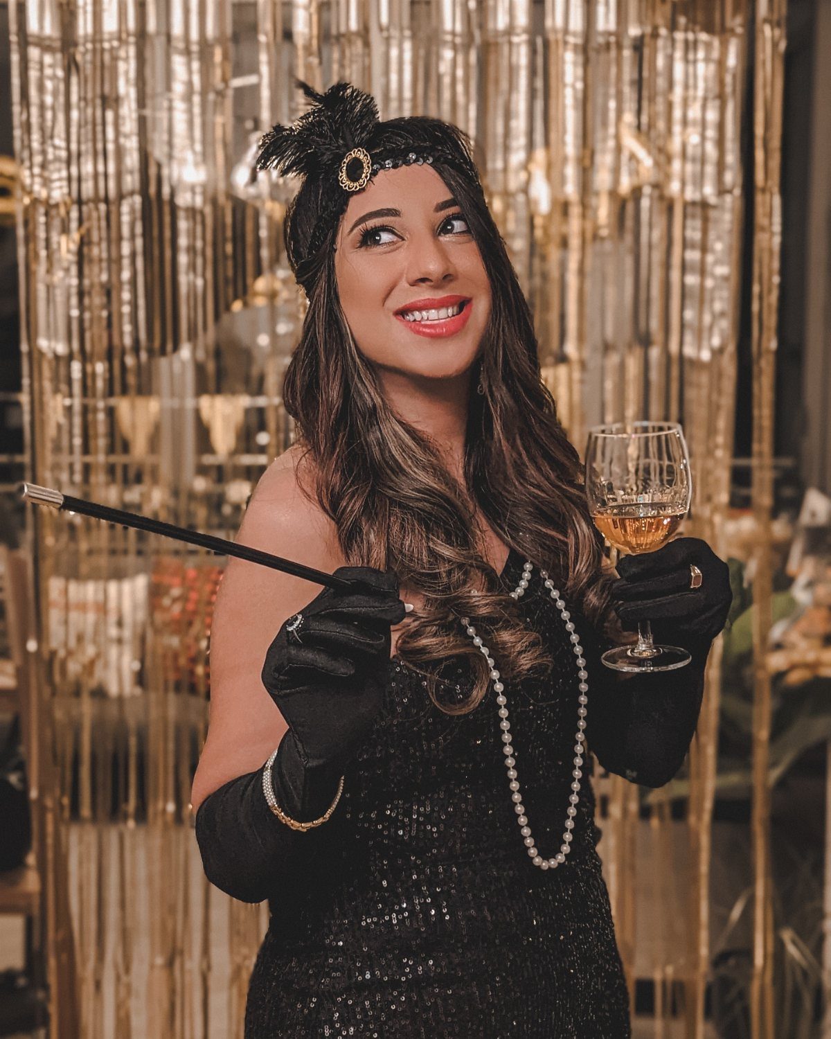 A woman in 1920s flapper costume holding a cocktail and a cigarette holder.