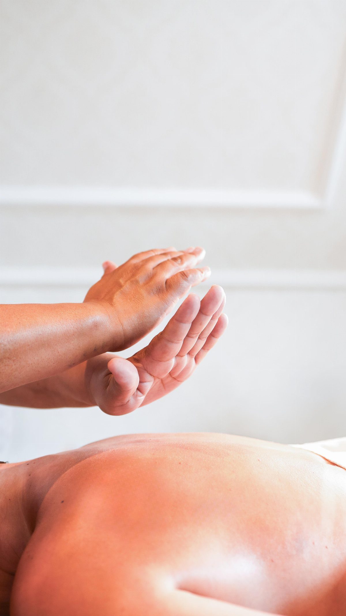 Hands performing a relaxing back massage on a person lying on a table.