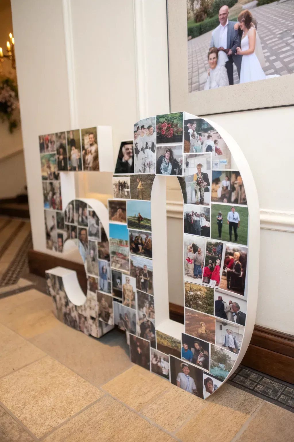 Large white numbers fifty covered in a collage of many small personal photographs standing indoors.
