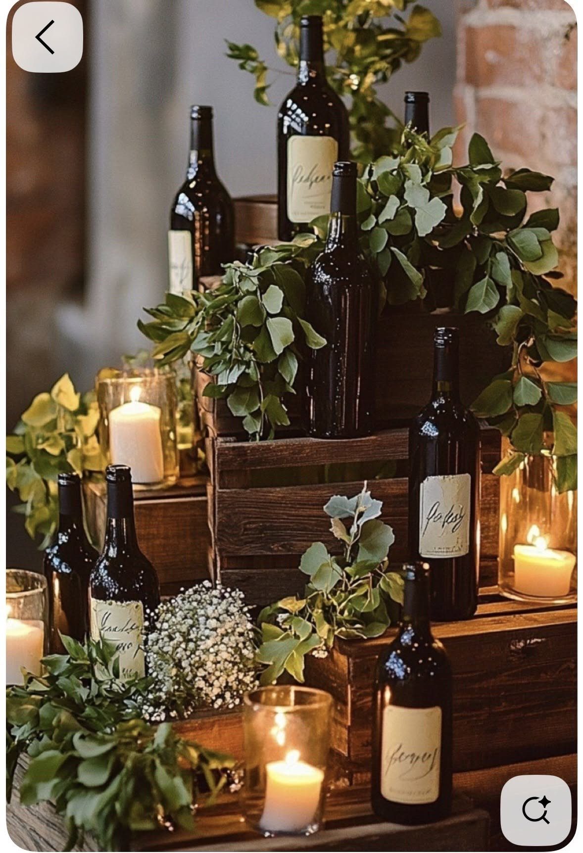 Wine bottles and greenery arranged with lit candles on rustic wooden crates.