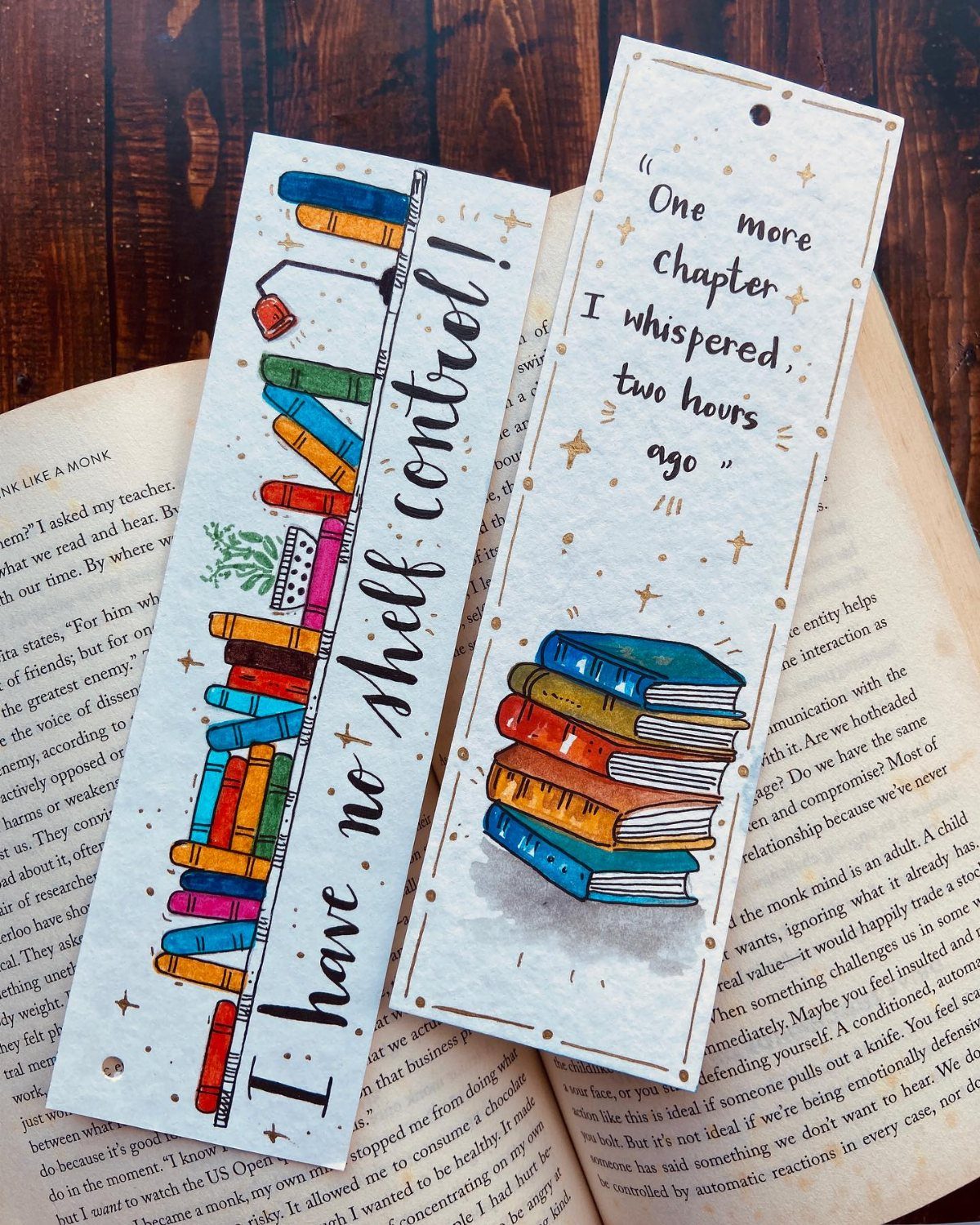Two decorative bookmarks with book illustrations resting on top of an open book.