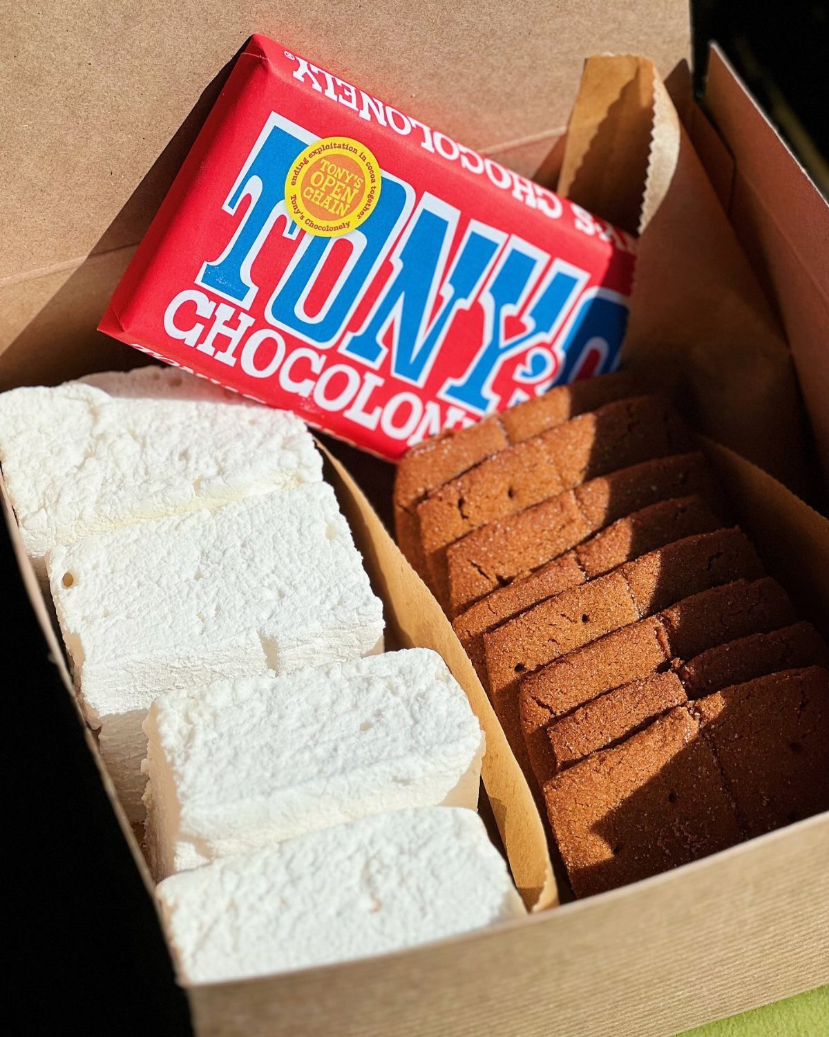 A cardboard box filled with chocolate, large white marshmallows, and graham crackers for s'mores.