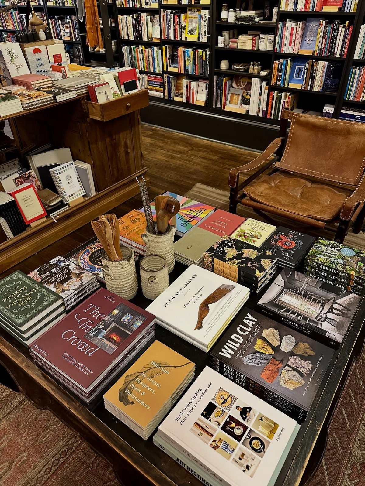Assorted hardcover coffee table books arranged on a dark wooden table in a bookstore setting.