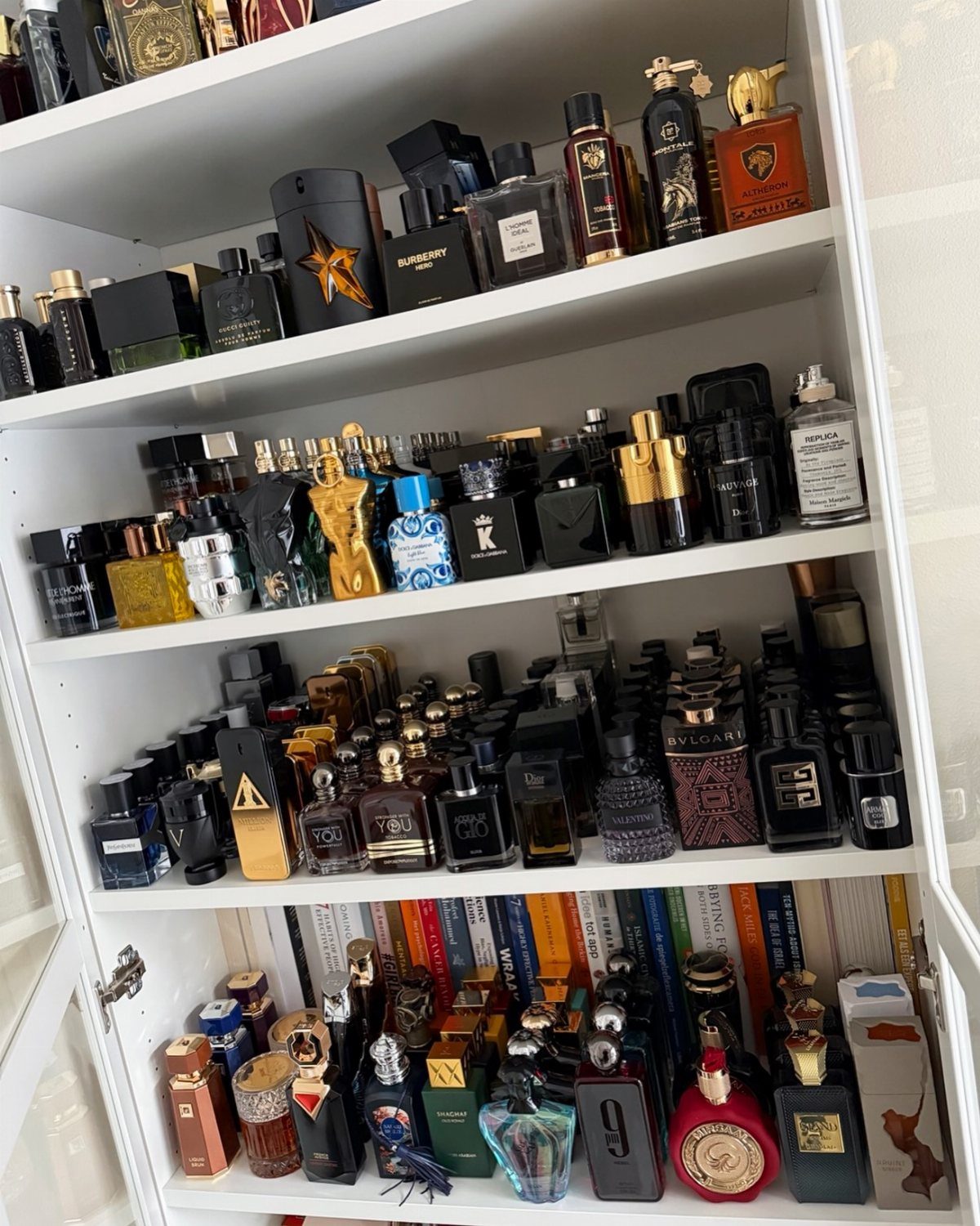 Numerous designer perfume and cologne bottles arranged on white shelves.