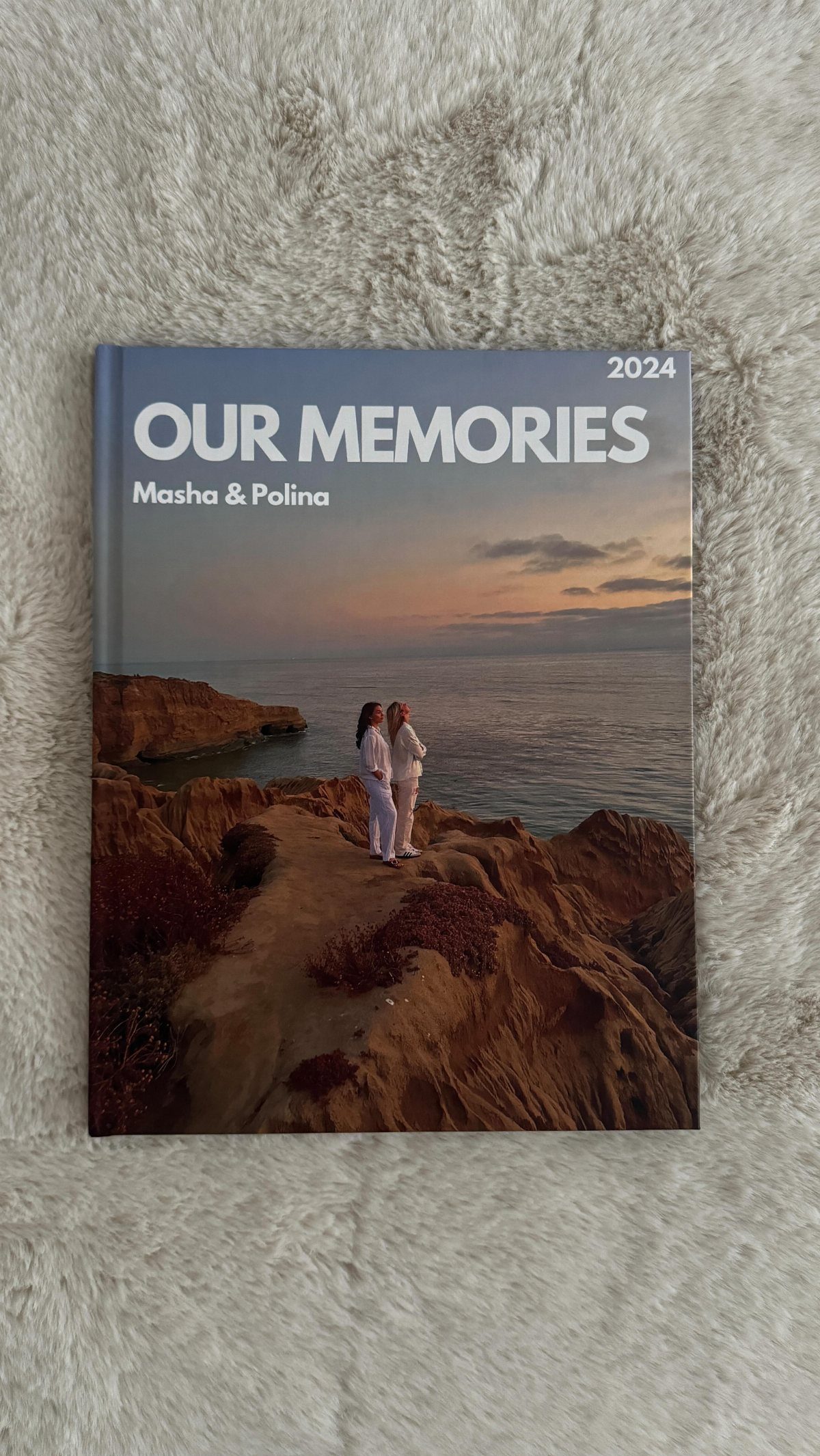 A memory book titled Our Memories resting on a white shaggy rug.