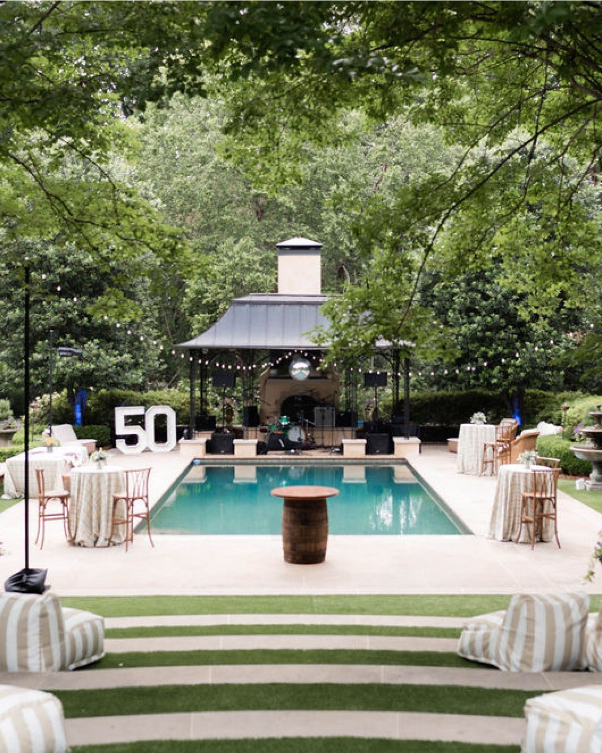 A backyard pool area decorated with string lights and large white numbers fifty for a celebration.