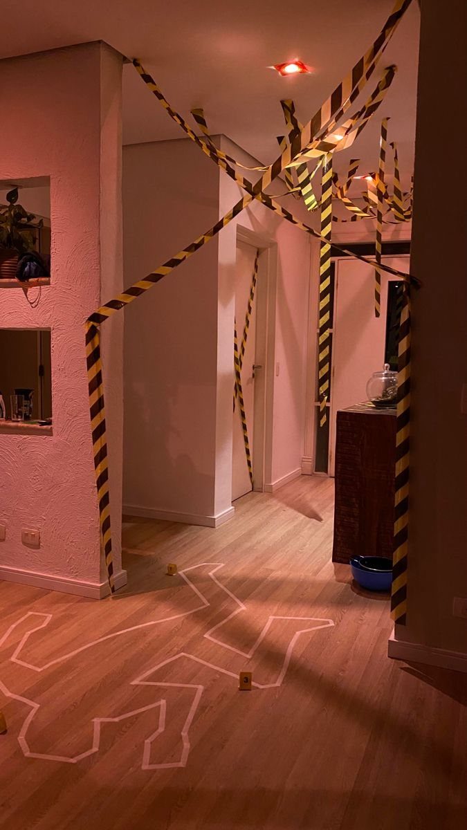 Caution tape hanging from the ceiling over a chalk body outline on the floor.