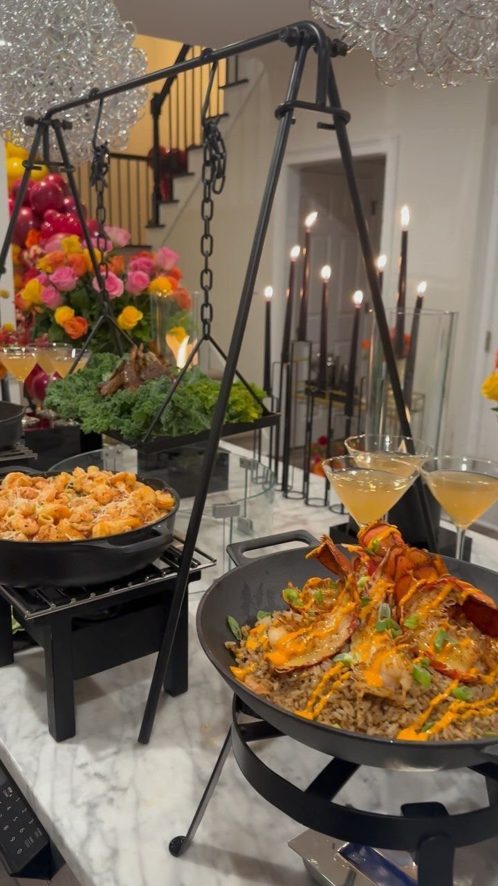 Lobster tails with sauce and fried rice served in a black pan on a marble counter.