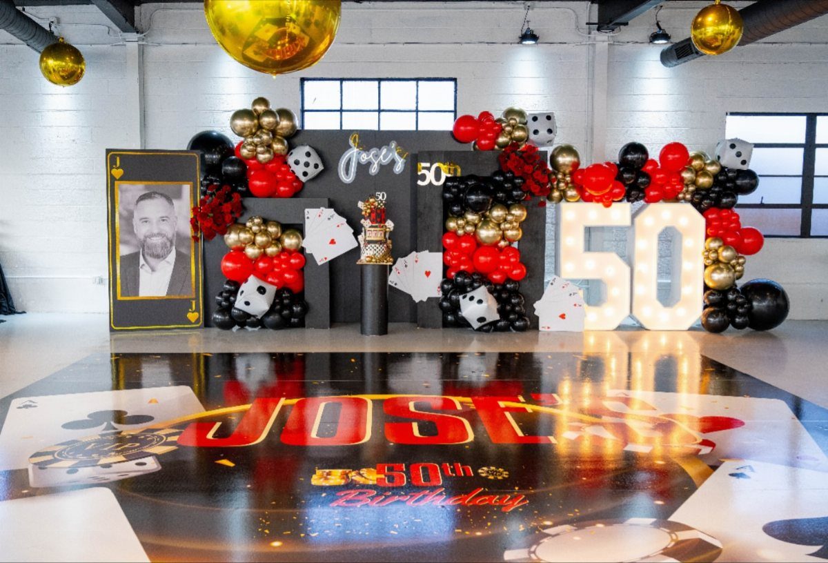 A 50th birthday party setup with casino-themed decorations, balloons, and large glowing numbers.