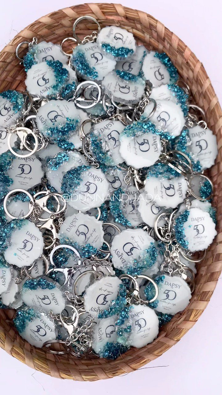 A woven basket overflowing with white and teal glittery keychains printed with the number 50.