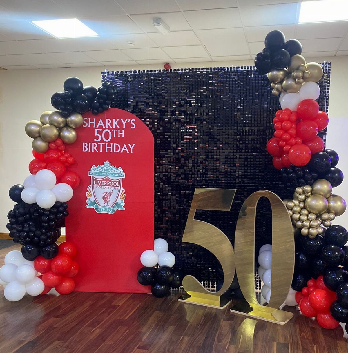 A 50th birthday party setup with Liverpool Football Club branding and balloon decor.