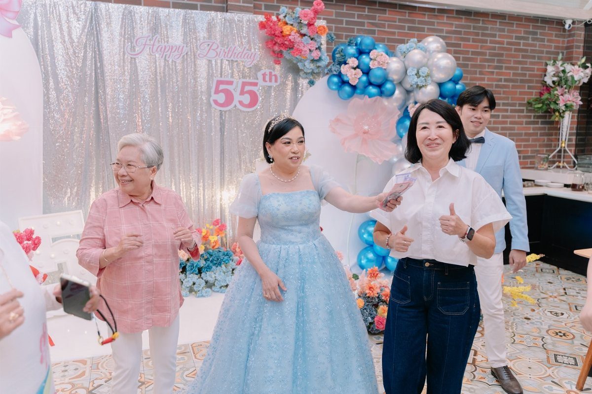 A woman in a blue gown celebrates her 55th birthday with friends and family.