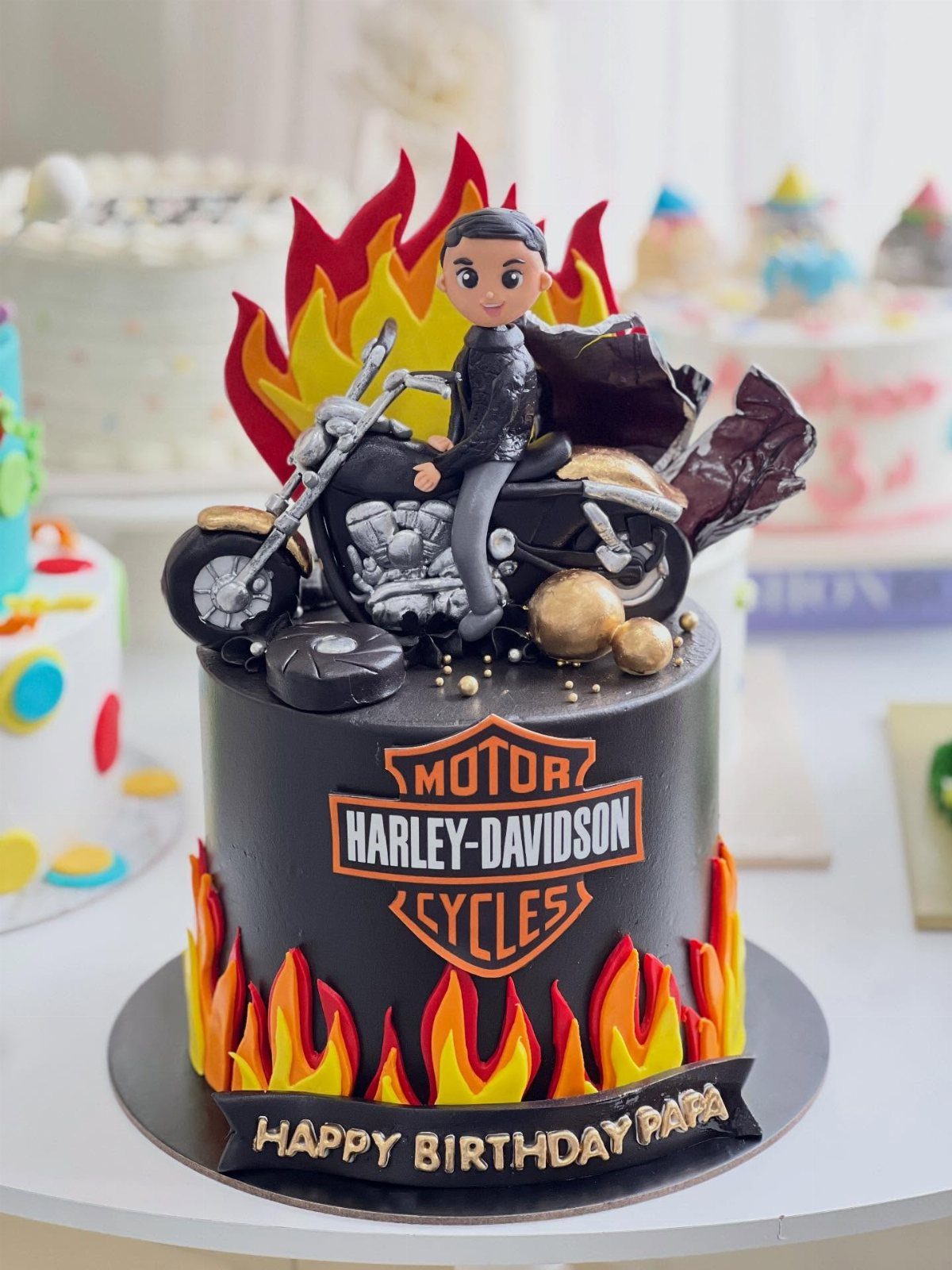 A black motorcycle-themed birthday cake with flames and a rider figurine.