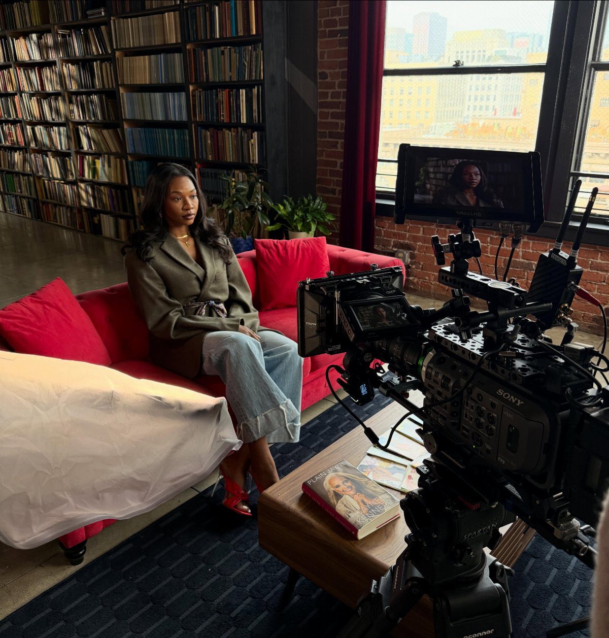 A woman being filmed by a professional video camera in a living room setting.