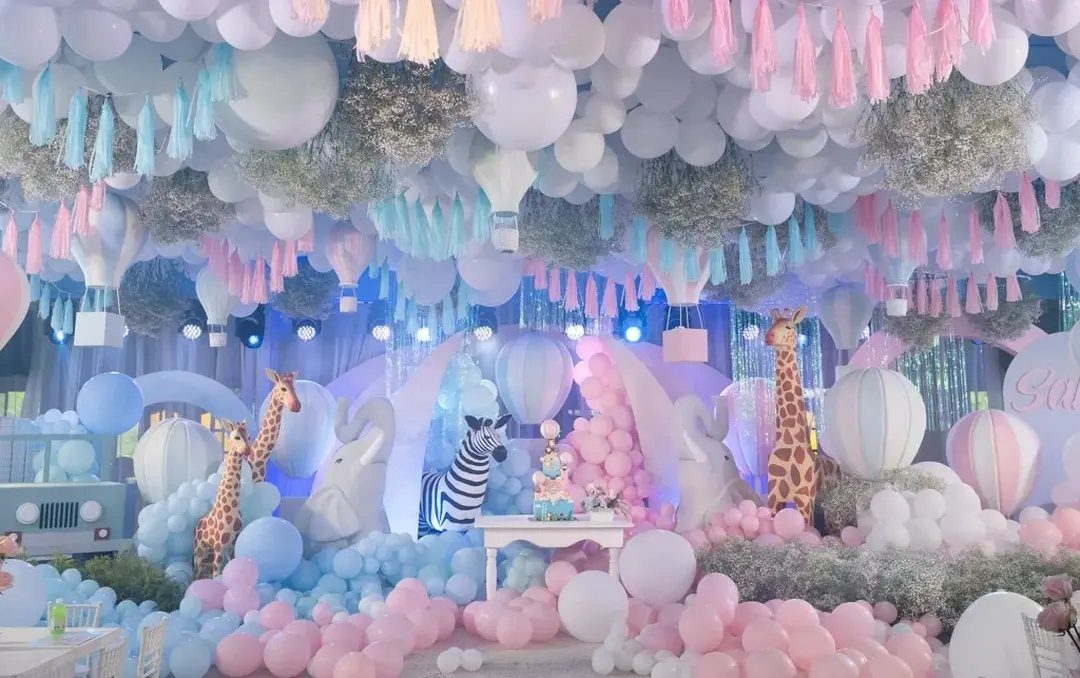 Large indoor party decoration with pastel balloons, animal cutouts, and hanging tassels.