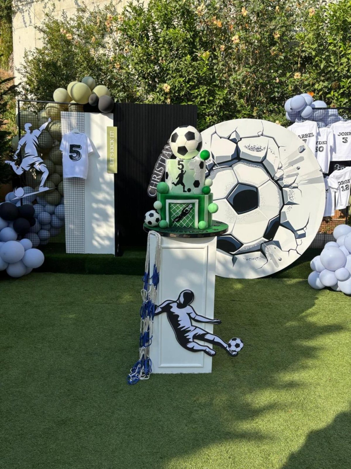 Soccer themed birthday decorations including a soccer ball cake and large circular soccer ball backdrop.
