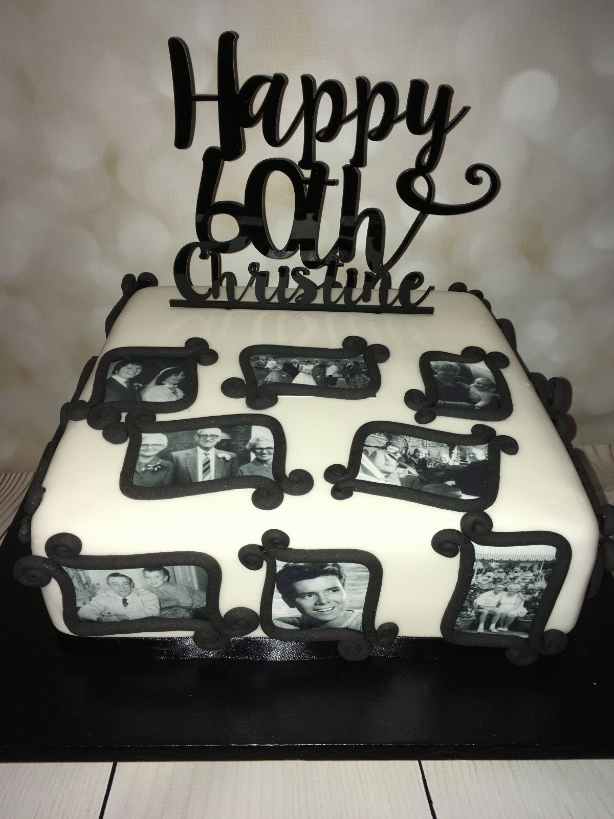 White sheet cake decorated with black and white edible family photos and a black 60th birthday topper.