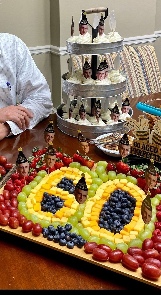 Fruit and cheese platter shaped like the number 60 next to tiered cupcakes.