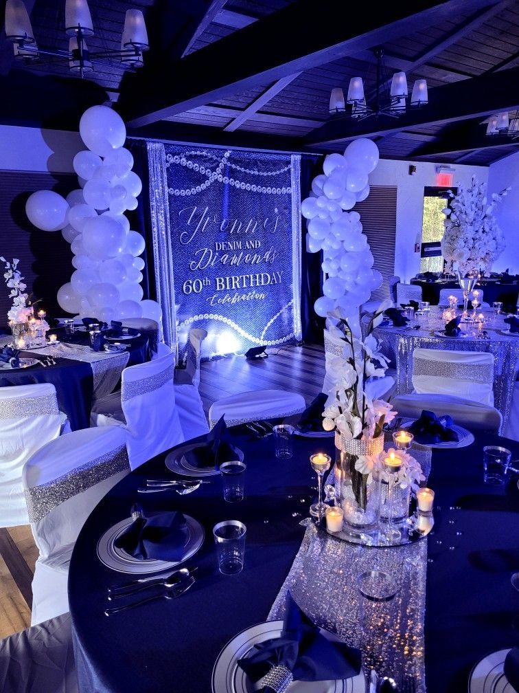Navy and silver decorated banquet tables with white balloon columns and a shimmering backdrop.