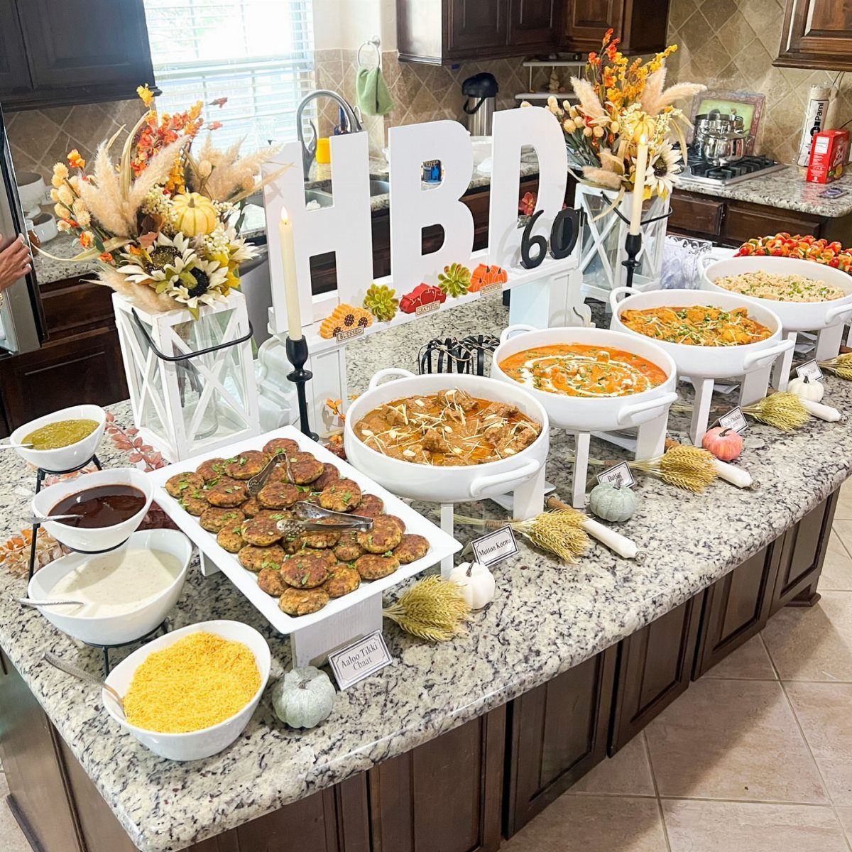 A large buffet of various cooked dishes served in white bowls on a granite kitchen island.