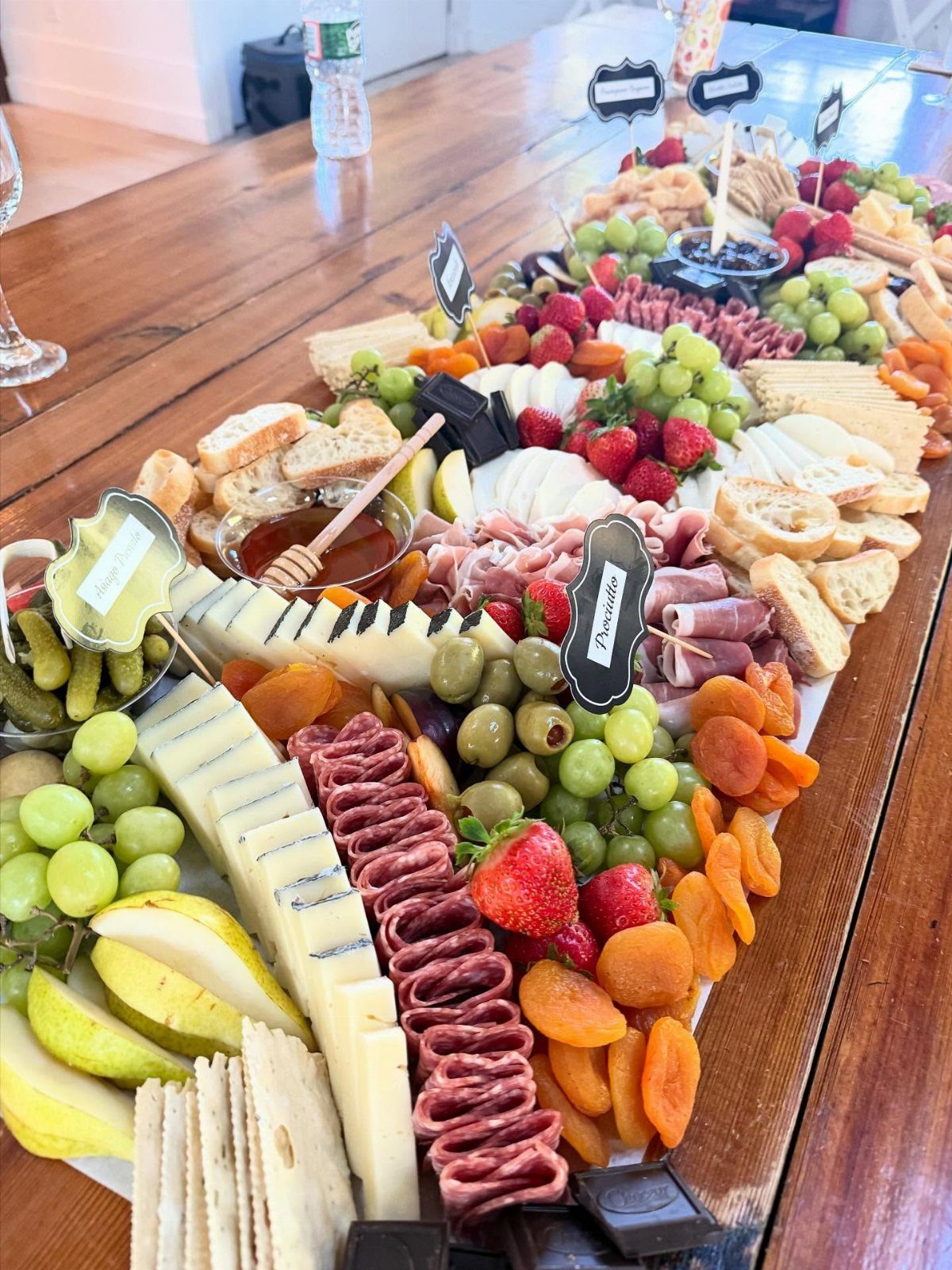 A large charcuterie board with meats, cheeses, fruits, and crackers on a wooden table.