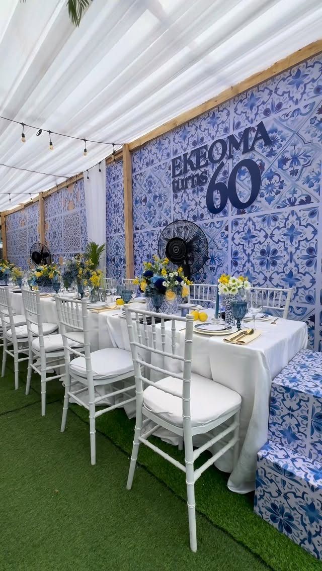 A decorated long dining table with blue and white patterned tile backdrops for a 60th birthday.