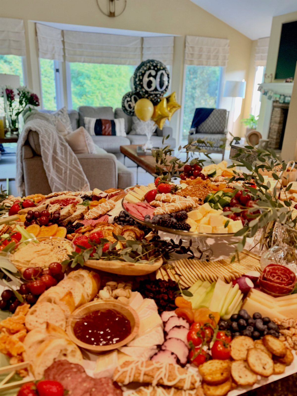 A large charcuterie spread with meats, cheeses, fruits, and crackers on a table.