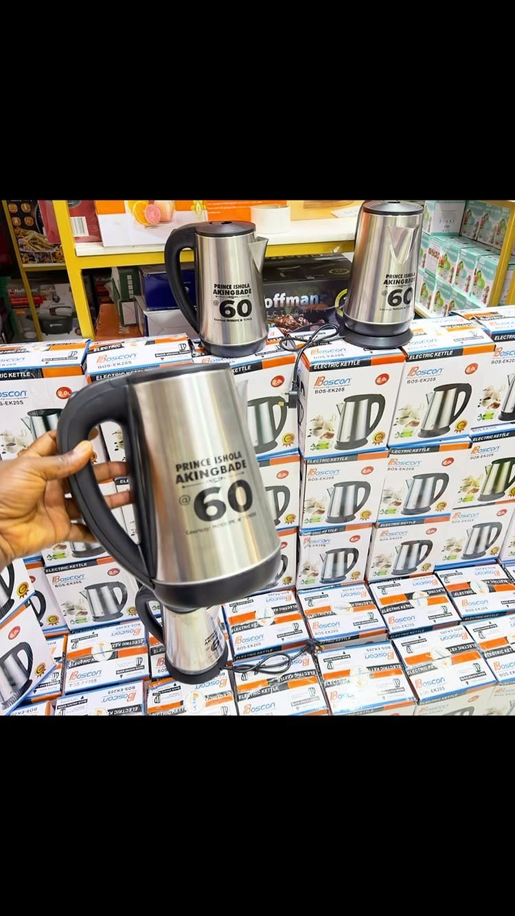 A hand holds a personalized stainless steel electric kettle with black printed text.